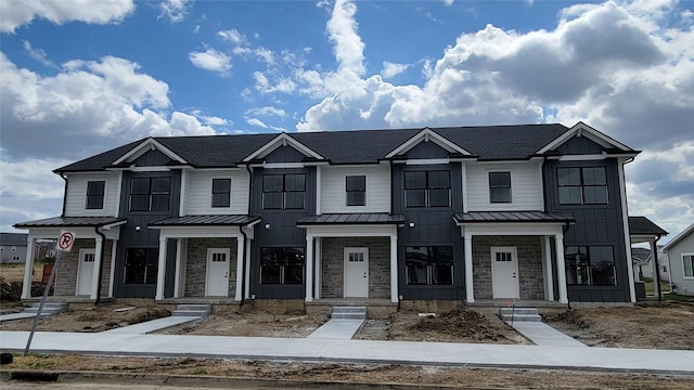 townhome / multi-family property with board and batten siding, a standing seam roof, stone siding, and metal roof