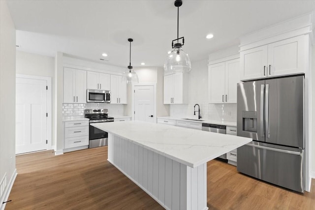 1991 S Warrior Ln, Waukee, IA 50263 - kitchen featuring stainless steel appliances, a sink, backsplash, a center island, and white cabinets