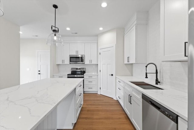 1991 S Warrior Ln, Waukee, IA 50263 - kitchen with appliances with stainless steel finishes, a sink, tasteful backsplash, white cabinetry, and recessed lighting