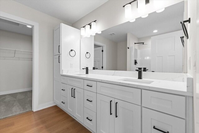 1991 S Warrior Ln, Waukee, IA 50263 - full bathroom featuring double vanity, baseboards, a shower, a walk in closet, and wood finished floors