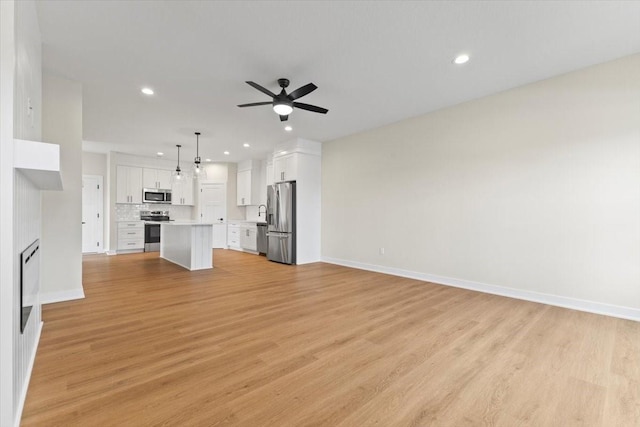 1991 S Warrior Ln, Waukee, IA 50263 - unfurnished living room with ceiling fan, recessed lighting, baseboards, and light wood finished floors