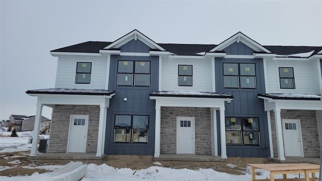 view of front facade with a standing seam roof, stone siding, board and batten siding, and metal roof