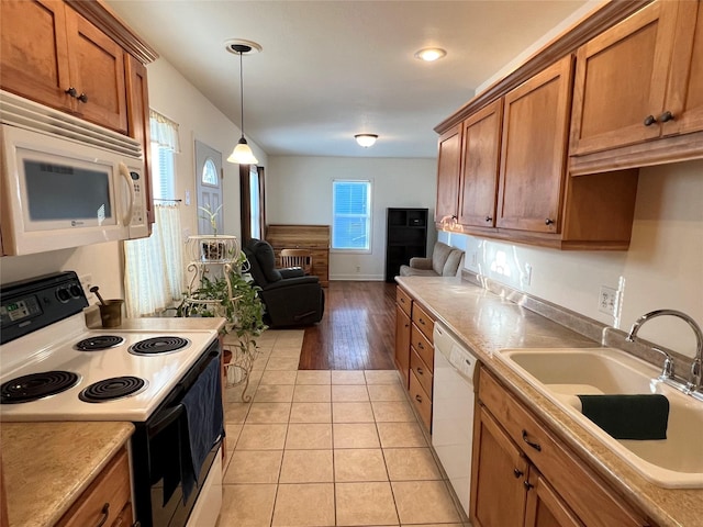 kitchen featuring white appliances, decorative light fixtures, light tile patterned flooring, and sink