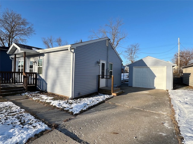 snow covered property featuring a garage and an outdoor structure