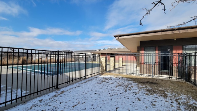 snow covered gate with a patio, a community pool, and fence