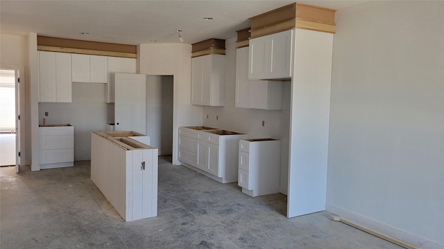 kitchen featuring white cabinetry, a kitchen island, concrete floors, and baseboards