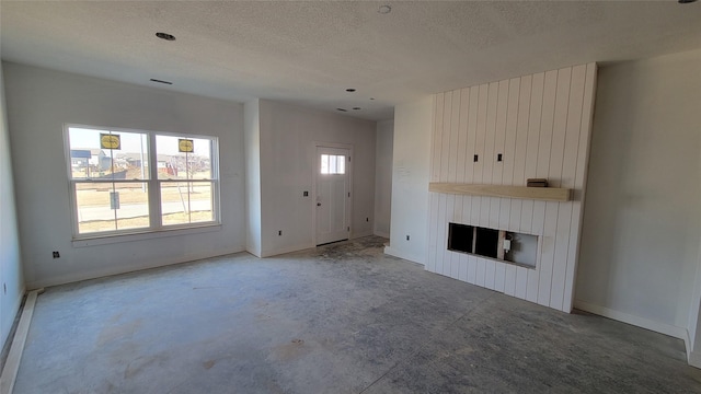 unfurnished living room featuring visible vents, a large fireplace, baseboards, baseboard heating, and a textured ceiling