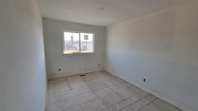 empty room with visible vents, baseboards, and a textured ceiling