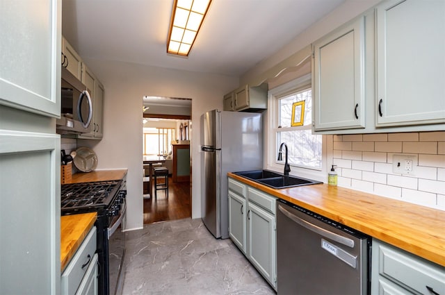 kitchen featuring appliances with stainless steel finishes, decorative backsplash, sink, and wood counters