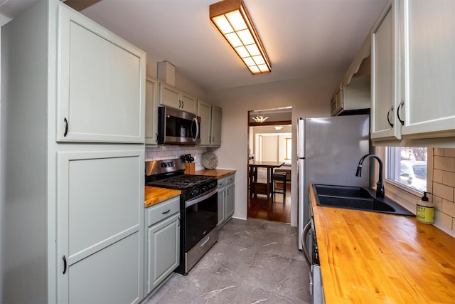 kitchen with sink, stainless steel appliances, butcher block counters, and decorative backsplash