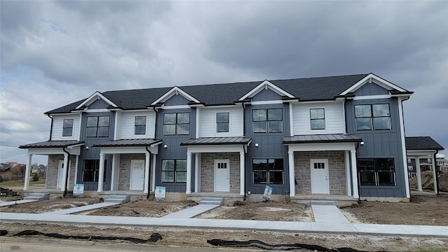multi unit property with board and batten siding, a shingled roof, a standing seam roof, and metal roof