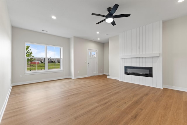1994 S Warrior Ln, Waukee, IA 50263 - unfurnished living room with a large fireplace, light wood-style floors, ceiling fan, healthy amount of natural light, and recessed lighting