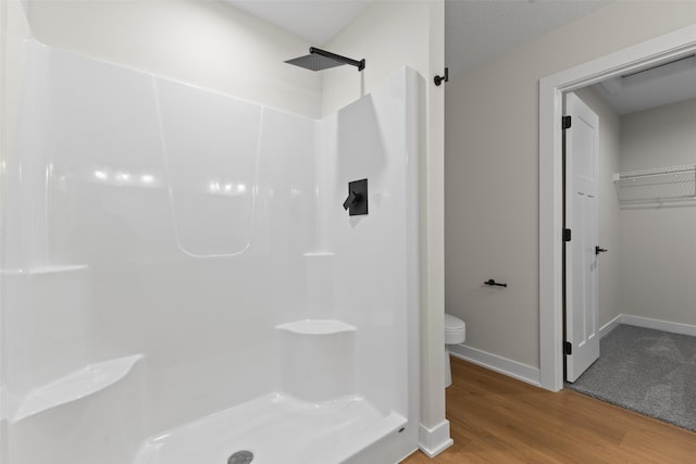1994 S Warrior Ln, Waukee, IA 50263 - bathroom with toilet, a shower, wood finished floors, and baseboards