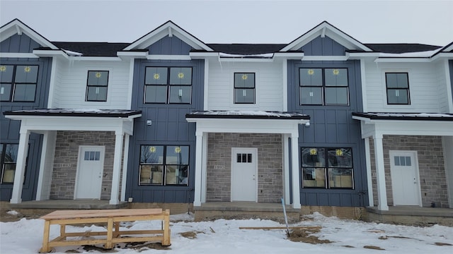 view of front of property with stone siding, board and batten siding, metal roof, and a standing seam roof