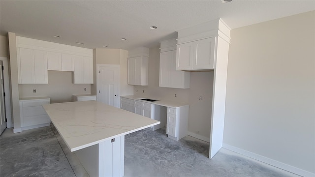 kitchen featuring white cabinetry, baseboards, concrete floors, and a center island