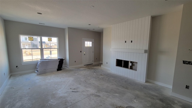 unfurnished living room featuring baseboards, a textured ceiling, and a fireplace