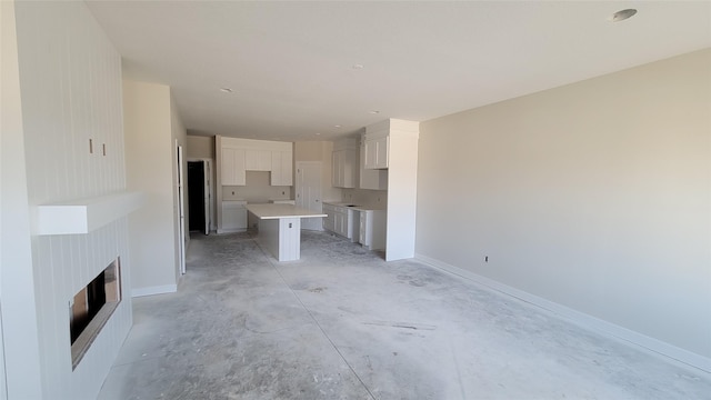 unfurnished living room with unfinished concrete floors, a fireplace, and baseboards