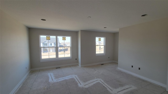 unfurnished room with baseboards and a textured ceiling