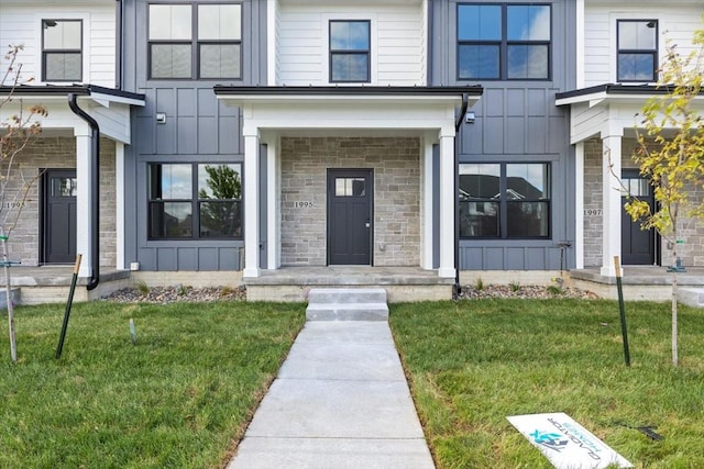 1995 S Warrior Ln, Waukee, IA 50263 - view of front of property with board and batten siding, a front yard, and stone siding