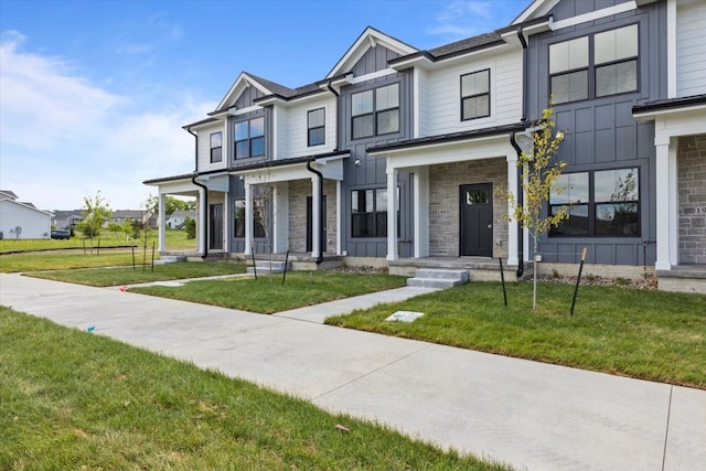 1995 S Warrior Ln, Waukee, IA 50263 - view of front facade featuring board and batten siding, stone siding, and a front yard