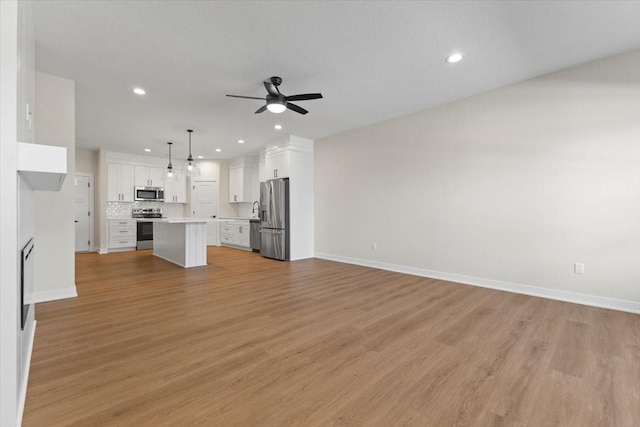 1995 S Warrior Ln, Waukee, IA 50263 - unfurnished living room with a ceiling fan, recessed lighting, baseboards, and light wood-type flooring