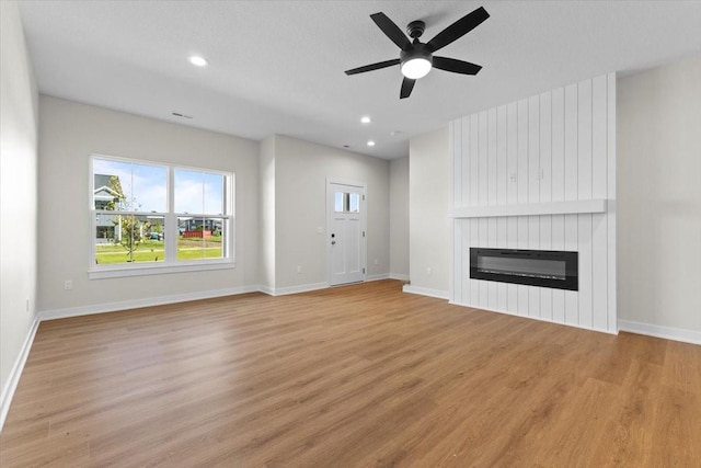 1995 S Warrior Ln, Waukee, IA 50263 - unfurnished living room with a ceiling fan, light wood-type flooring, a large fireplace, and recessed lighting