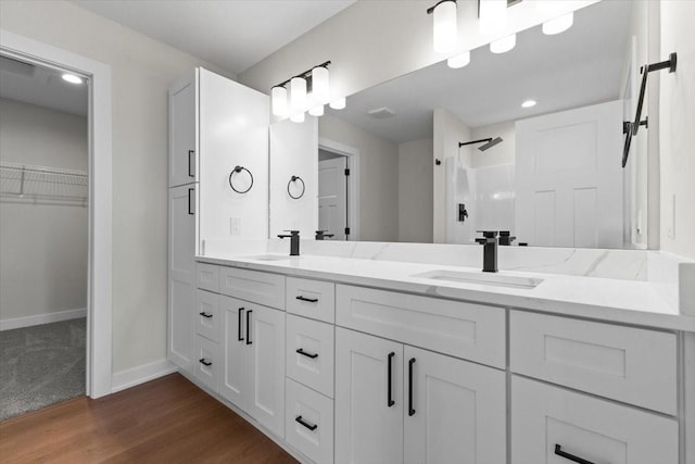 1995 S Warrior Ln, Waukee, IA 50263 - full bathroom featuring double vanity, a shower, baseboards, wood finished floors, and a spacious closet