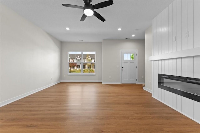 1995 S Warrior Ln, Waukee, IA 50263 - unfurnished living room with a glass covered fireplace, ceiling fan, recessed lighting, wood finished floors, and baseboards