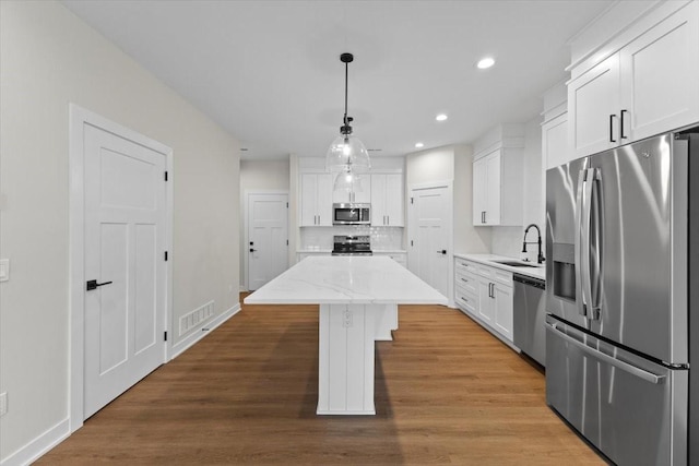 1995 S Warrior Ln, Waukee, IA 50263 - kitchen with stainless steel appliances, a center island, recessed lighting, white cabinets, and tasteful backsplash