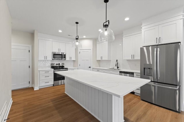 1995 S Warrior Ln, Waukee, IA 50263 - kitchen featuring stainless steel appliances, tasteful backsplash, a sink, a kitchen island, and white cabinets