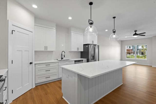 1995 S Warrior Ln, Waukee, IA 50263 - kitchen with a sink, stainless steel appliances, light wood-type flooring, white cabinetry, and open floor plan