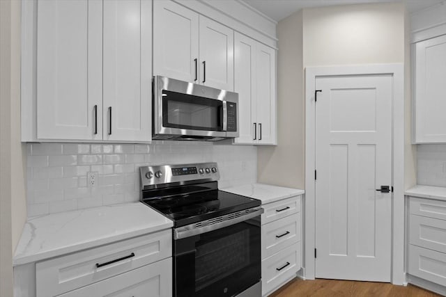 1995 S Warrior Ln, Waukee, IA 50263 - kitchen featuring stainless steel appliances, white cabinets, tasteful backsplash, and light stone counters