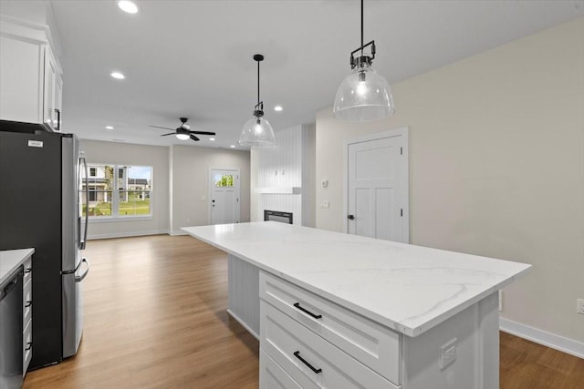 1995 S Warrior Ln, Waukee, IA 50263 - kitchen featuring freestanding refrigerator, a ceiling fan, white cabinets, a fireplace, and open floor plan