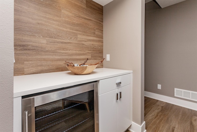 details with beverage cooler, hardwood / wood-style floors, and white cabinets