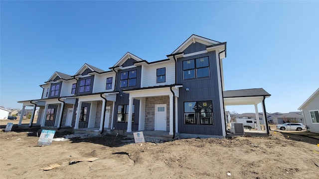 view of front of property with a porch, stone siding, board and batten siding, and central AC