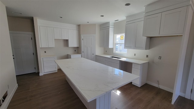 kitchen with white cabinetry, a kitchen island, dark wood-type flooring, and baseboards