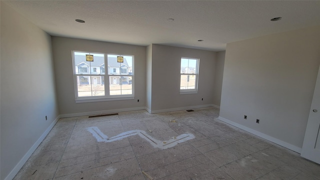 unfurnished room featuring visible vents, a textured ceiling, and baseboards