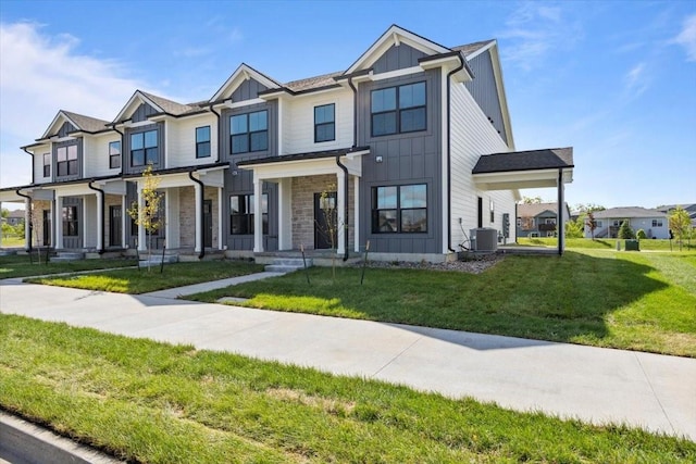 1997 S Warrior Ln, Waukee, IA 50263 - view of front facade with board and batten siding, central air condition unit, a front lawn, and stone siding
