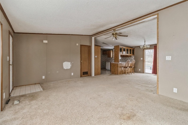 unfurnished living room with ceiling fan with notable chandelier, a textured ceiling, ornamental molding, and carpet floors