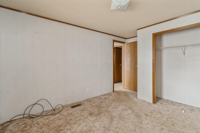 unfurnished bedroom with a closet, light carpet, a textured ceiling, and crown molding