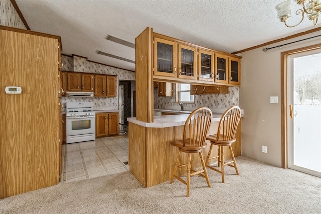 kitchen featuring a kitchen breakfast bar, light colored carpet, kitchen peninsula, white gas range oven, and a textured ceiling