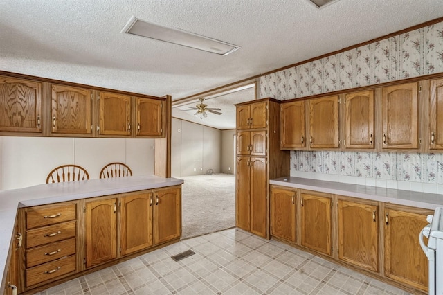 kitchen featuring white stove, a textured ceiling, ceiling fan, and light colored carpet