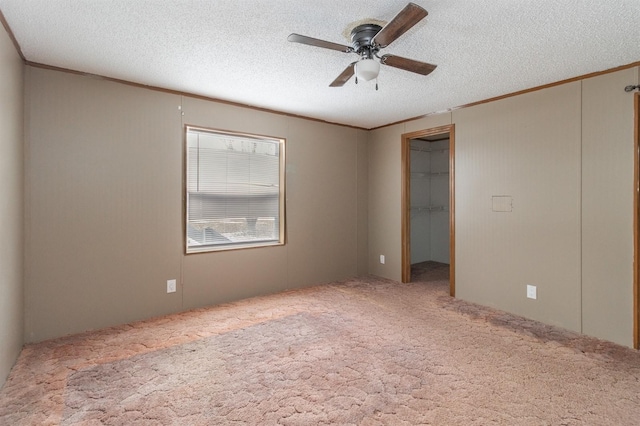 carpeted empty room featuring ceiling fan, ornamental molding, and a textured ceiling