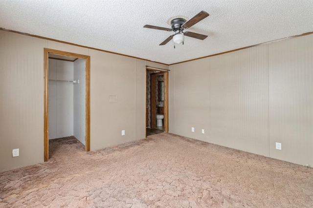 unfurnished bedroom featuring ensuite bathroom, a closet, carpet floors, ornamental molding, and ceiling fan