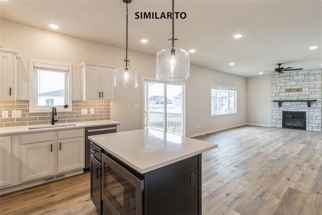 kitchen featuring black microwave, white cabinetry, decorative backsplash, and sink