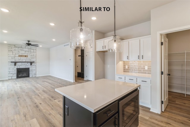 kitchen featuring ceiling fan, built in microwave, a kitchen island, pendant lighting, and white cabinets