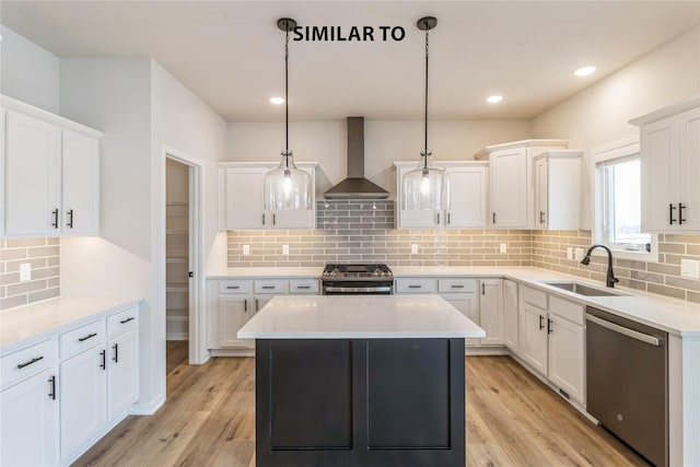 kitchen with hanging light fixtures, white cabinets, appliances with stainless steel finishes, and wall chimney exhaust hood