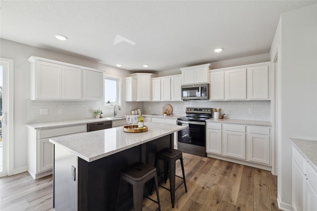 546 34th St SE, Altoona, IA 50009 - kitchen with stainless steel appliances, light wood-style flooring, white cabinets, decorative backsplash, and recessed lighting