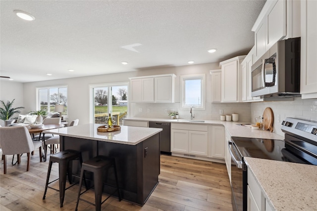 546 34th St SE, Altoona, IA 50009 - kitchen with appliances with stainless steel finishes, a kitchen breakfast bar, decorative backsplash, a center island, and recessed lighting