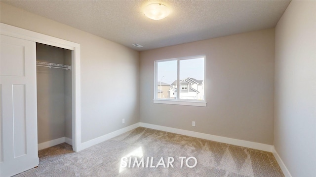 unfurnished bedroom featuring a textured ceiling, light colored carpet, and a closet